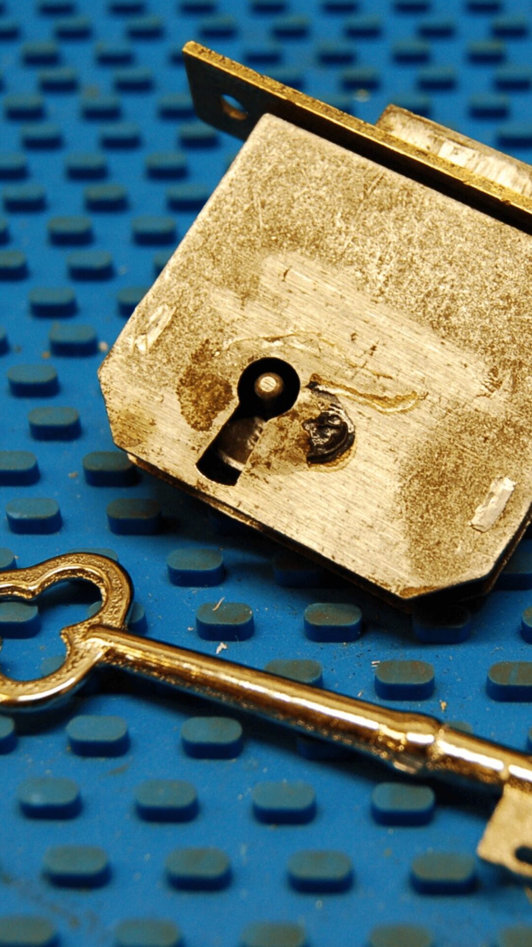 A brass antique lock and skeleton key sit on a blue pinning mat at Able Locksmiths in Frederick, MD.