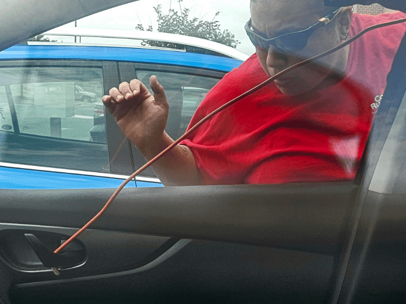 An emergency car lockout in Frederick MD. A technician in a red shirt for Able Locksmiths, LLC unlocks the car. 